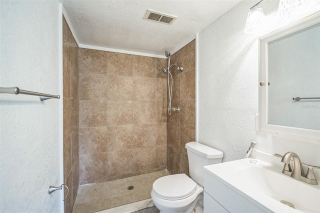 bathroom with tiled shower, vanity, a textured ceiling, and toilet