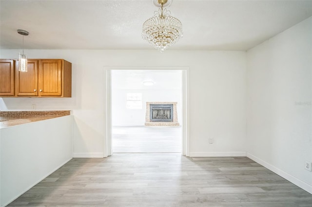 unfurnished dining area with light wood-type flooring and an inviting chandelier