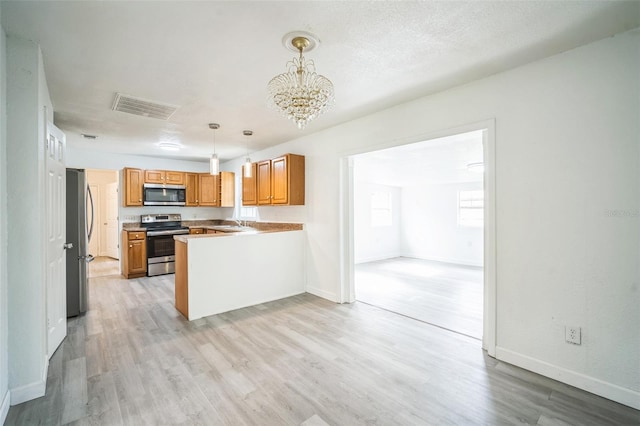 kitchen featuring stainless steel appliances, decorative light fixtures, a notable chandelier, kitchen peninsula, and light hardwood / wood-style flooring