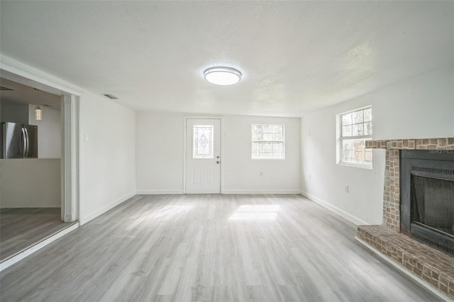 unfurnished living room featuring a textured ceiling, hardwood / wood-style floors, and a fireplace