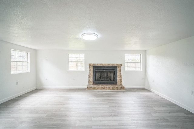 unfurnished living room with a textured ceiling, light hardwood / wood-style floors, and plenty of natural light