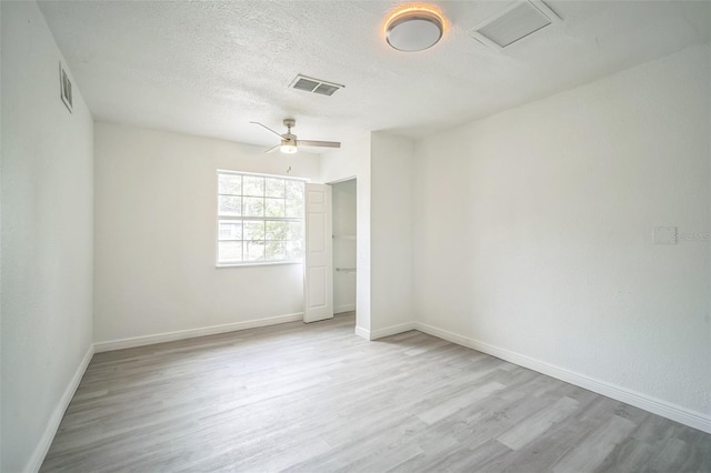 unfurnished room with ceiling fan, a textured ceiling, and light wood-type flooring