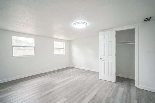 unfurnished bedroom featuring light hardwood / wood-style flooring, a textured ceiling, and a closet