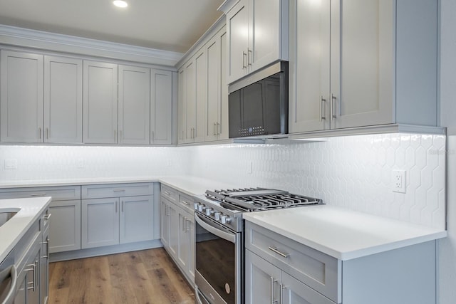 kitchen featuring stainless steel appliances, gray cabinets, wood-type flooring, and tasteful backsplash