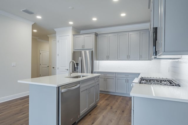 kitchen featuring dark hardwood / wood-style floors, stainless steel appliances, a center island with sink, crown molding, and sink