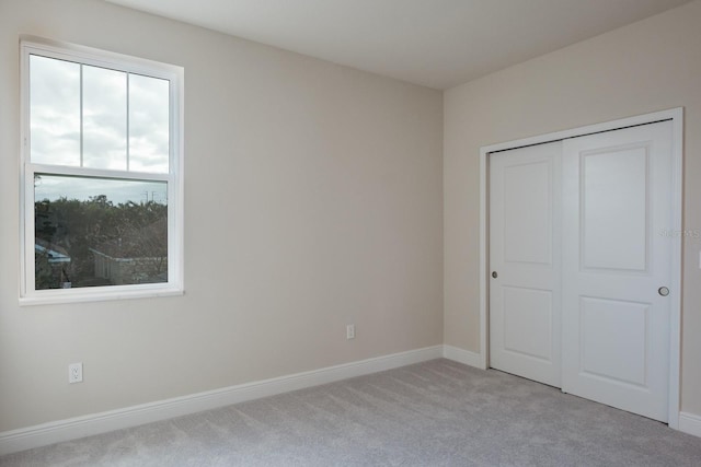 unfurnished bedroom with a closet and light carpet