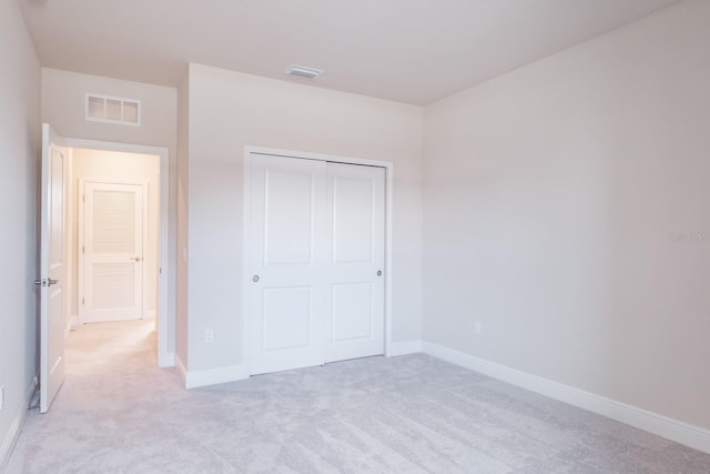 unfurnished bedroom featuring light colored carpet and a closet