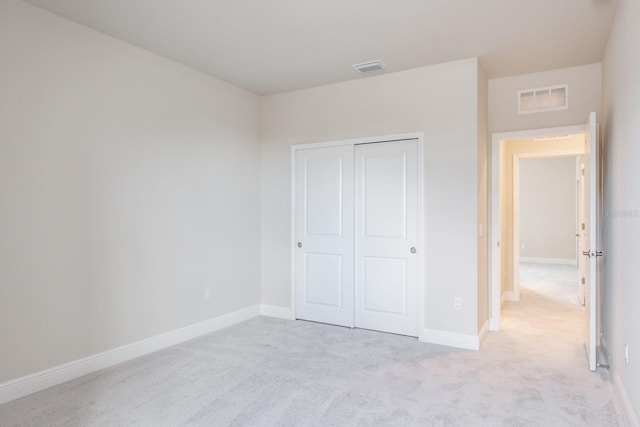 unfurnished bedroom with a closet and light colored carpet