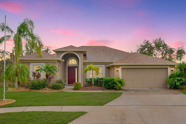 mediterranean / spanish-style home with a garage and a yard