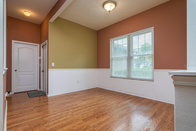 unfurnished room featuring hardwood / wood-style flooring and beamed ceiling