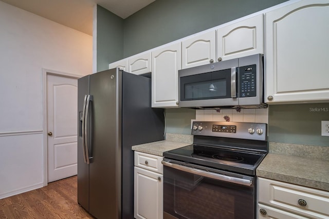 kitchen with white cabinetry, appliances with stainless steel finishes, dark hardwood / wood-style floors, and backsplash