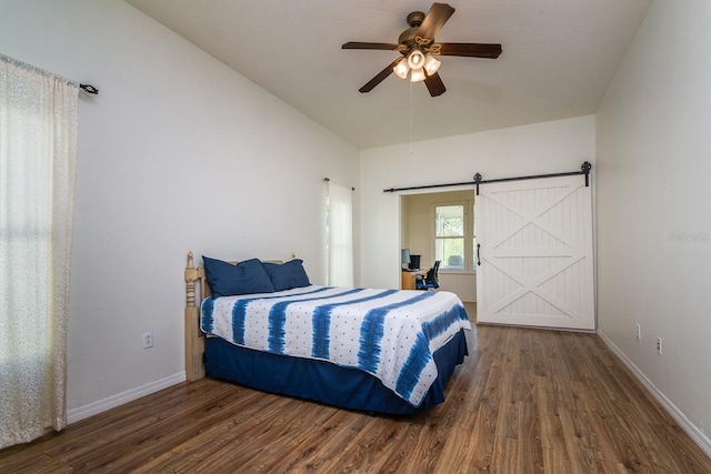 bedroom featuring a barn door, dark hardwood / wood-style floors, and ceiling fan