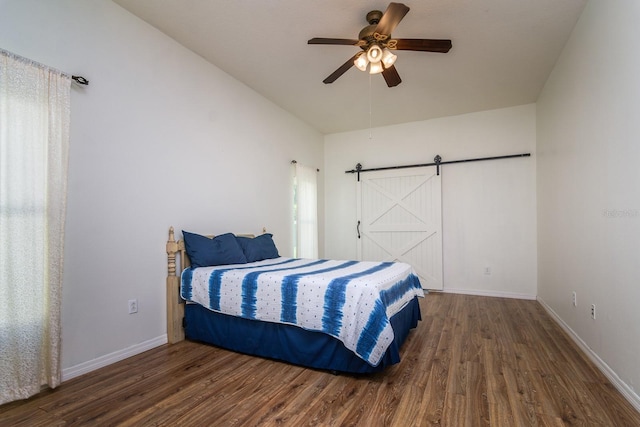 bedroom with dark wood-type flooring, a barn door, and ceiling fan