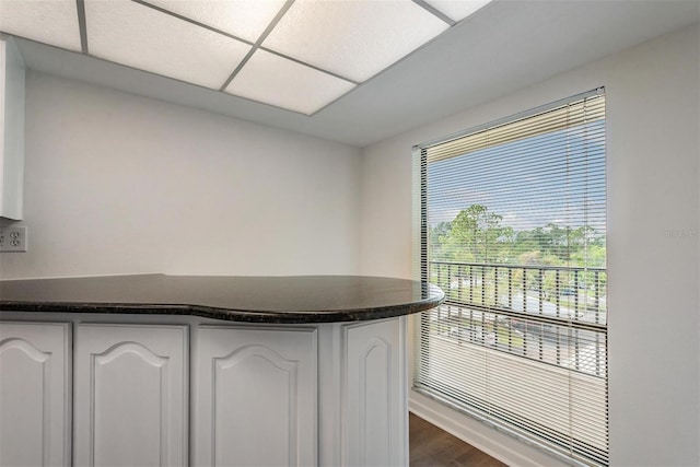 kitchen with white cabinets, a paneled ceiling, and dark wood-type flooring