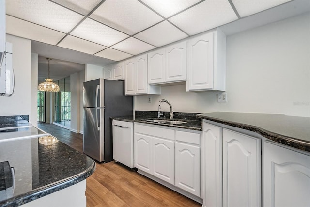 kitchen with white dishwasher, white cabinets, sink, pendant lighting, and light hardwood / wood-style flooring