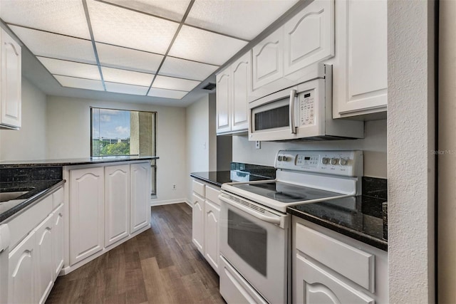 kitchen featuring white appliances, dark hardwood / wood-style flooring, a drop ceiling, white cabinets, and kitchen peninsula