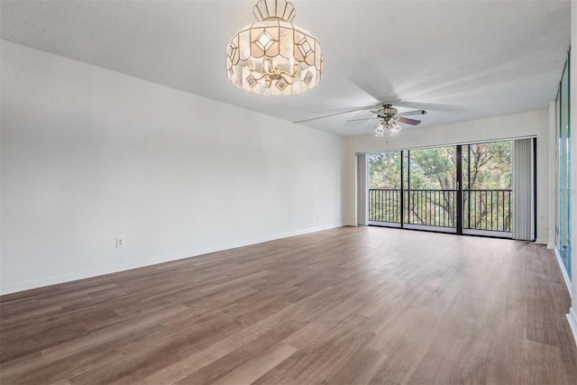 unfurnished room featuring a textured ceiling, hardwood / wood-style flooring, and ceiling fan with notable chandelier