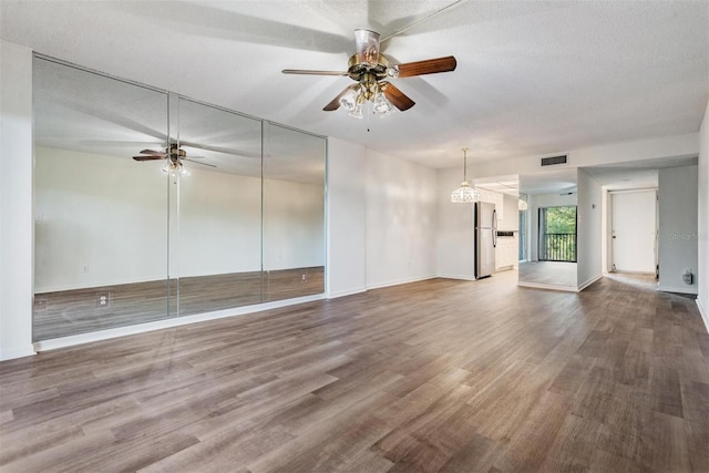 unfurnished living room featuring hardwood / wood-style floors, ceiling fan, and a textured ceiling