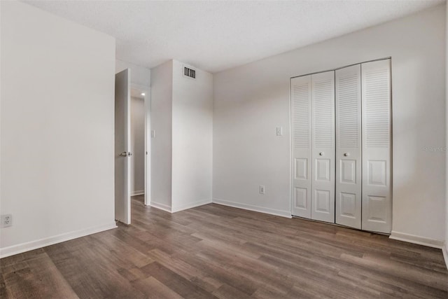 unfurnished bedroom featuring dark wood-type flooring, a closet, and a textured ceiling