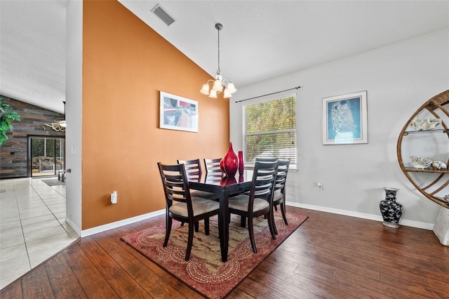 dining room with hardwood / wood-style flooring, vaulted ceiling, and a notable chandelier