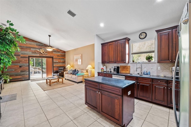 kitchen with wood walls, a wealth of natural light, sink, and vaulted ceiling