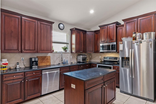 kitchen featuring appliances with stainless steel finishes, light tile patterned floors, sink, lofted ceiling, and a center island