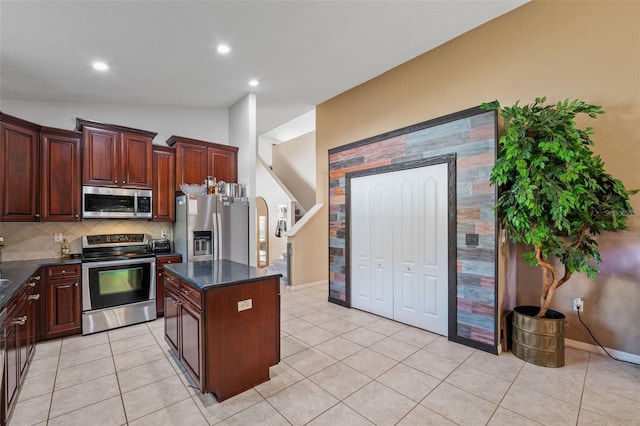 kitchen featuring tasteful backsplash, light tile patterned flooring, stainless steel appliances, lofted ceiling, and a center island