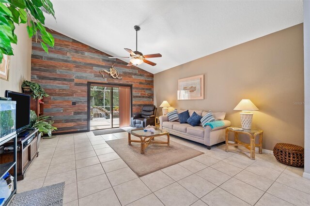 living room with lofted ceiling, wooden walls, ceiling fan, and light tile patterned floors