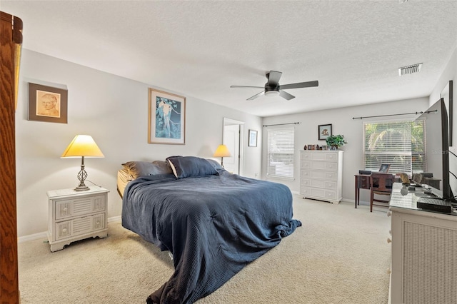 bedroom with a textured ceiling, light carpet, and ceiling fan