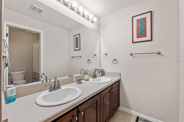 bathroom with toilet, vanity, and tile patterned flooring