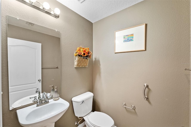 bathroom featuring a textured ceiling, toilet, and sink