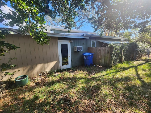 rear view of property featuring a lawn and a wall mounted air conditioner