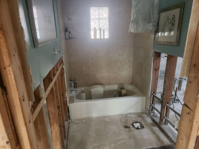 bathroom featuring a bath and tile walls