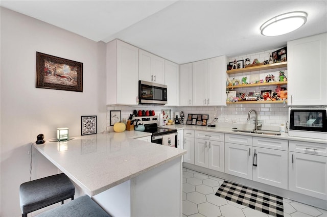 kitchen with white cabinetry, sink, stainless steel appliances, a kitchen breakfast bar, and kitchen peninsula