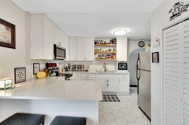 kitchen with a breakfast bar, white cabinets, sink, kitchen peninsula, and stainless steel appliances