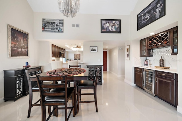 tiled dining room with a chandelier, bar area, and beverage cooler