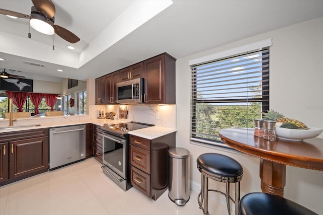 kitchen featuring backsplash, kitchen peninsula, dark brown cabinets, and stainless steel appliances