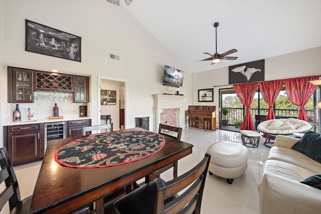 dining space with bar, ceiling fan, high vaulted ceiling, and beverage cooler