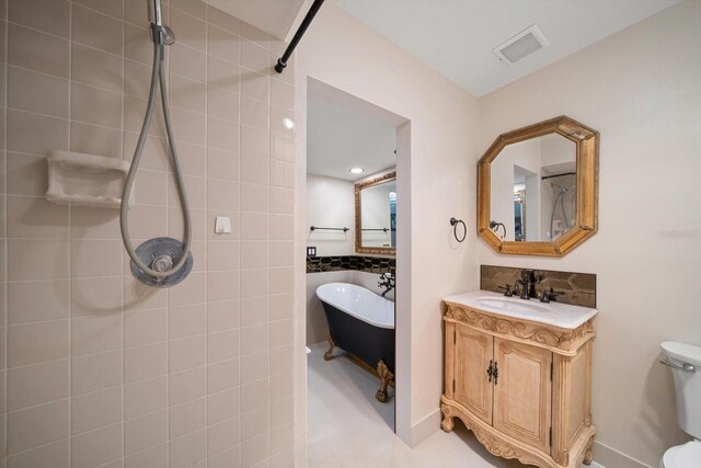 bathroom featuring tile patterned flooring, vanity, toilet, and a bathing tub