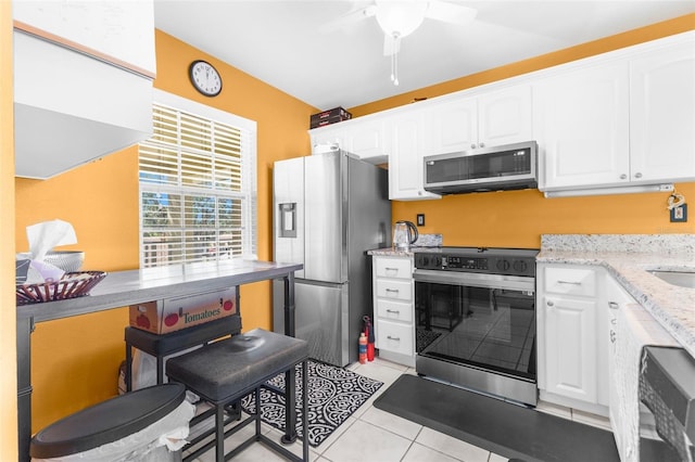 kitchen with ceiling fan, light stone countertops, light tile patterned floors, appliances with stainless steel finishes, and white cabinetry