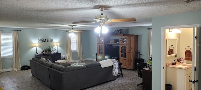 tiled living room with ceiling fan, a textured ceiling, and sink