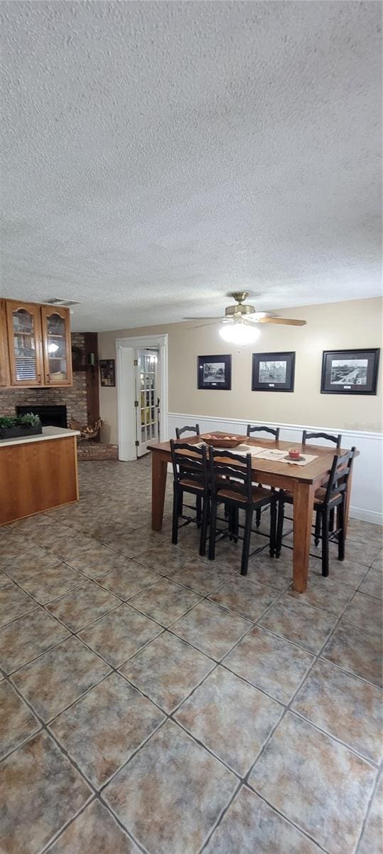 tiled dining room with ceiling fan and a textured ceiling