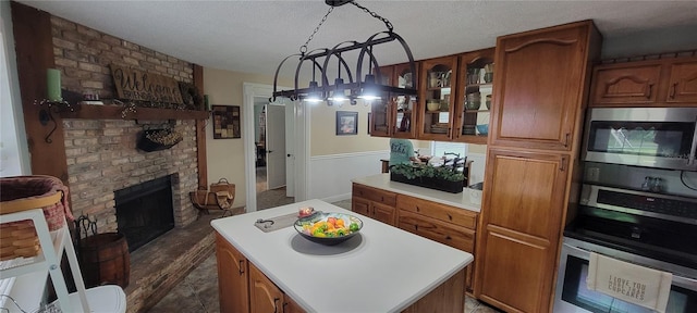 kitchen featuring a fireplace, stainless steel appliances, a textured ceiling, dark hardwood / wood-style flooring, and hanging light fixtures