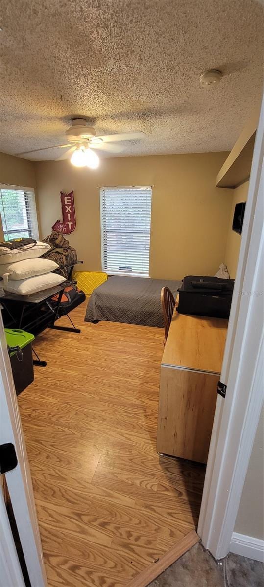 bedroom featuring ceiling fan, multiple windows, and a textured ceiling