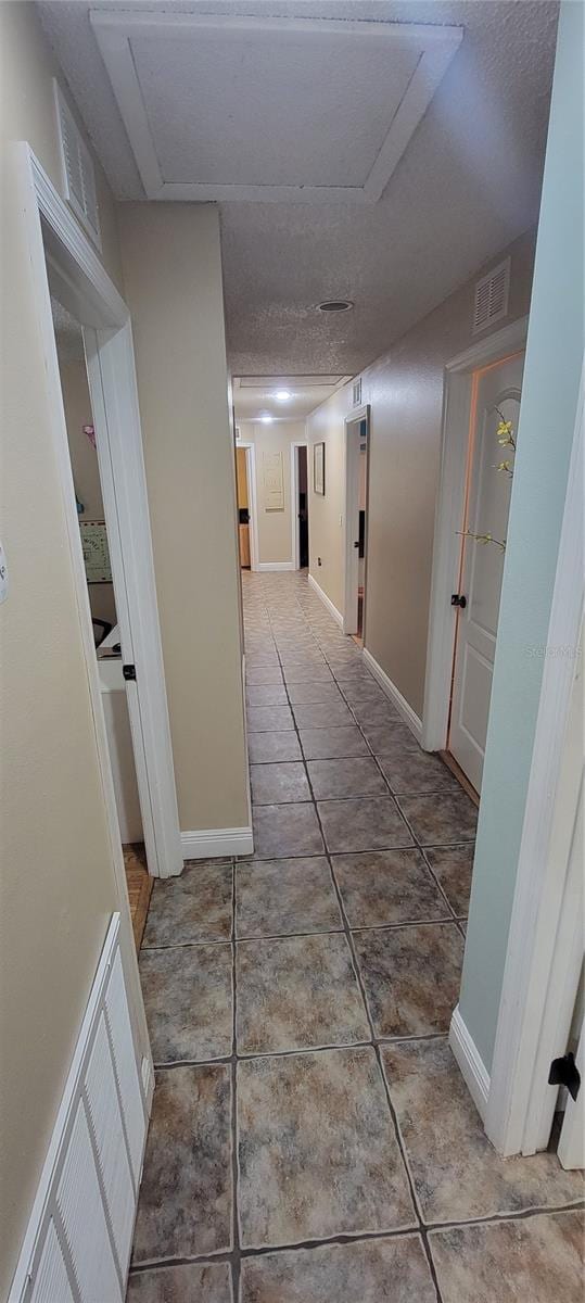 hallway featuring a textured ceiling and tile patterned flooring