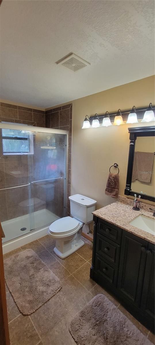 bathroom with walk in shower, vanity, toilet, and tile patterned floors