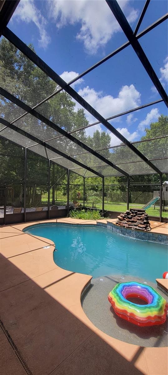 view of swimming pool featuring a patio and glass enclosure