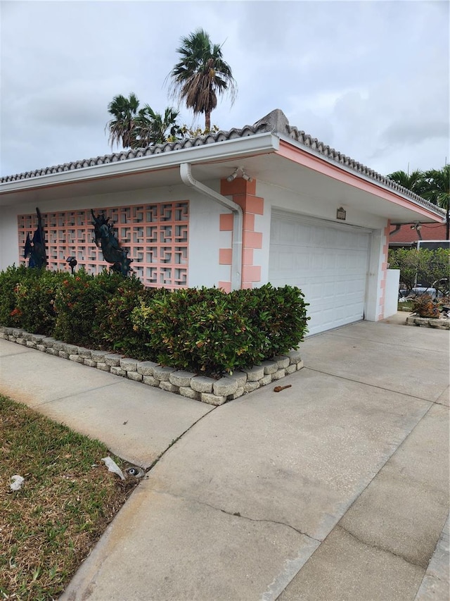 12520 4th St E, Treasure Island, FL 33706 - view of home's exterior featuring a garage, driveway, a tiled roof, and stucco siding