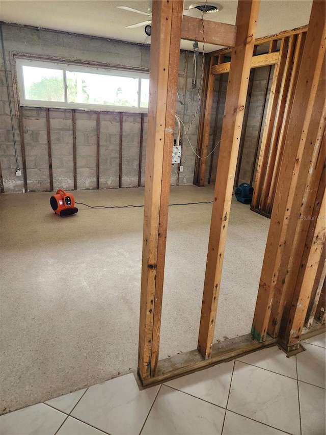 basement with ceiling fan and tile patterned flooring