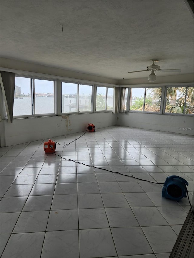 unfurnished sunroom with a water view and ceiling fan